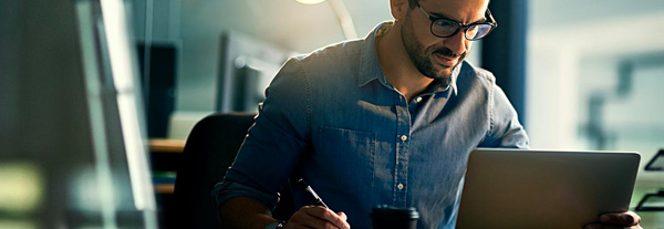Man in front of his desk, and focus on his tablet in a corporate environment.